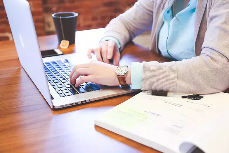 Mujer trabajando en su escritorio en computadora.
