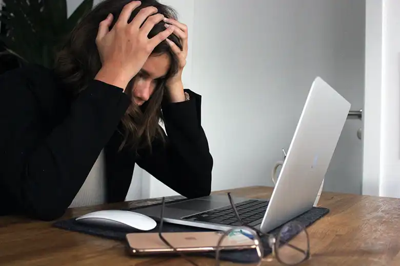 Mujer frustrada en su escritorio frente a su laptop